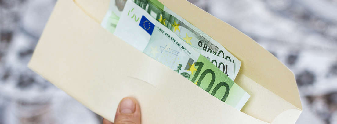 Mano sujetando un sobre con billetes de euro