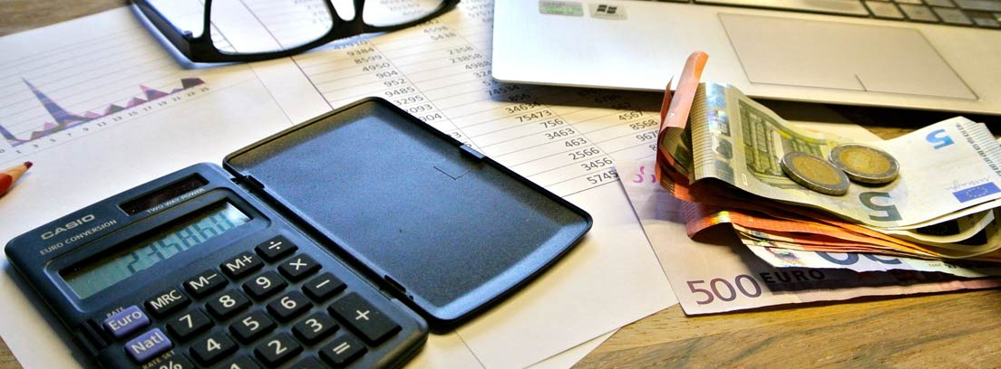 Mesa con calculadora, papeles, billetes y monedas