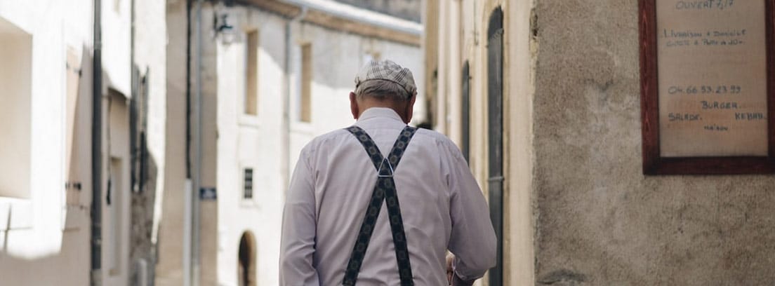 Persona de avanzada edad camina por la calle de un pueblo italiano
