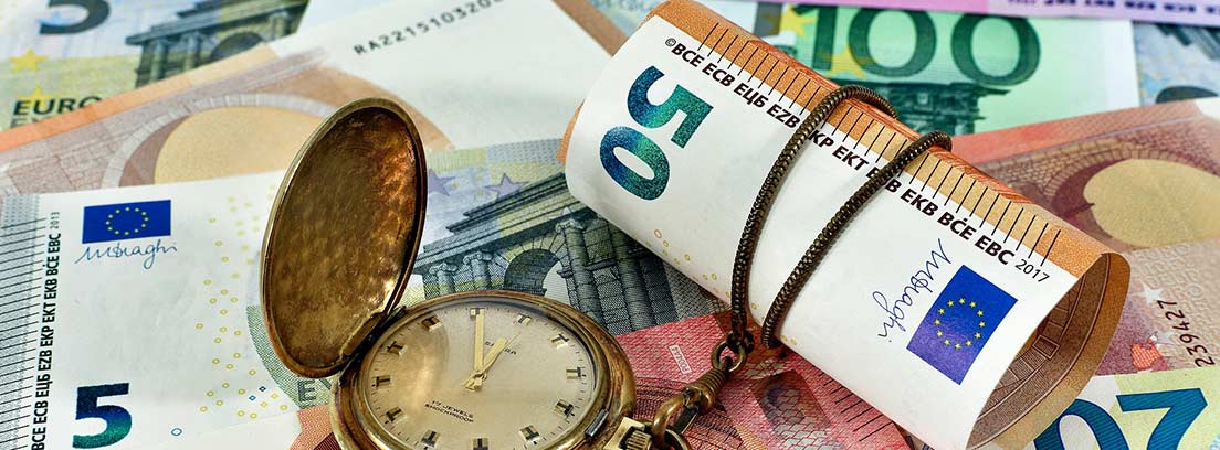Varios billetes en una mesa con un reloj que sostiene uno de 50 euros
