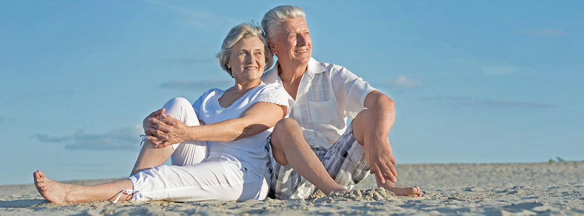 Hombre y mujer mayores sentados en la playa