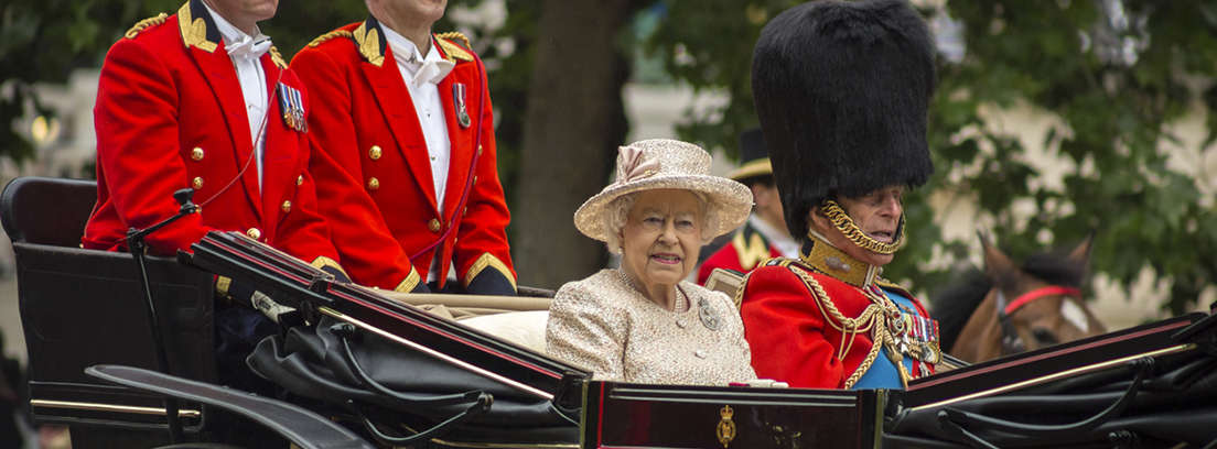 Reina Isabel II con chaqueta rosa, gorro y guantes.