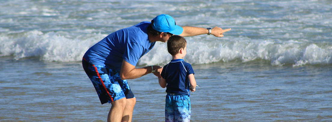 Hombre y niño de espaldas mirando el mar