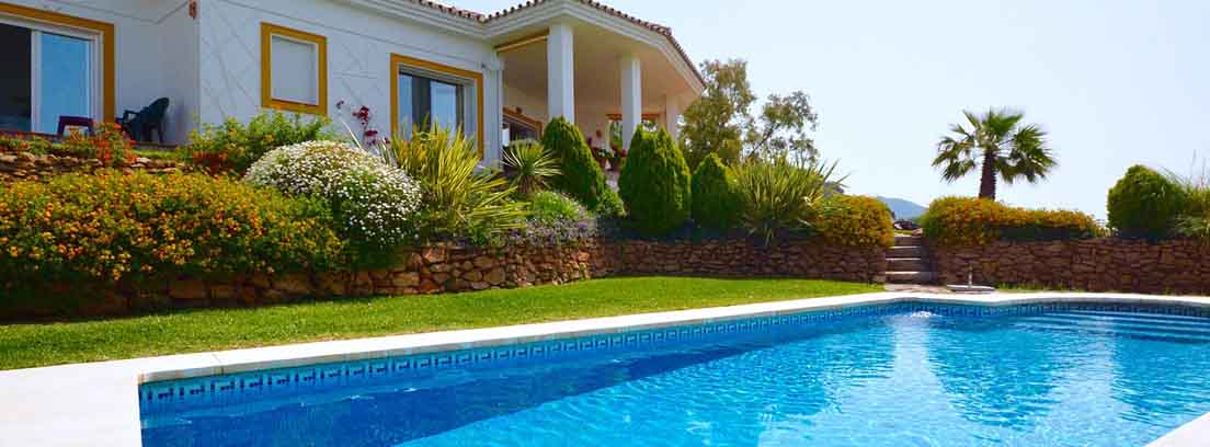 Piscina exterior con agua y fondo azul al lado de casa y jardines