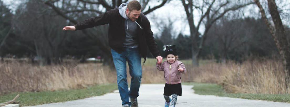 Padre corre con su hija pequeña de la mano