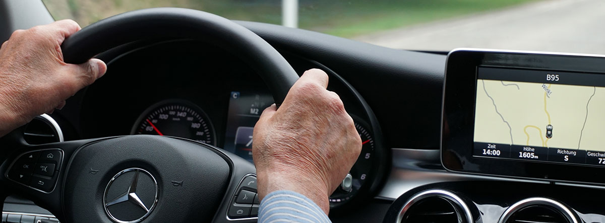 Manos de una persona mayor sobre el volante de un coche Mercedes