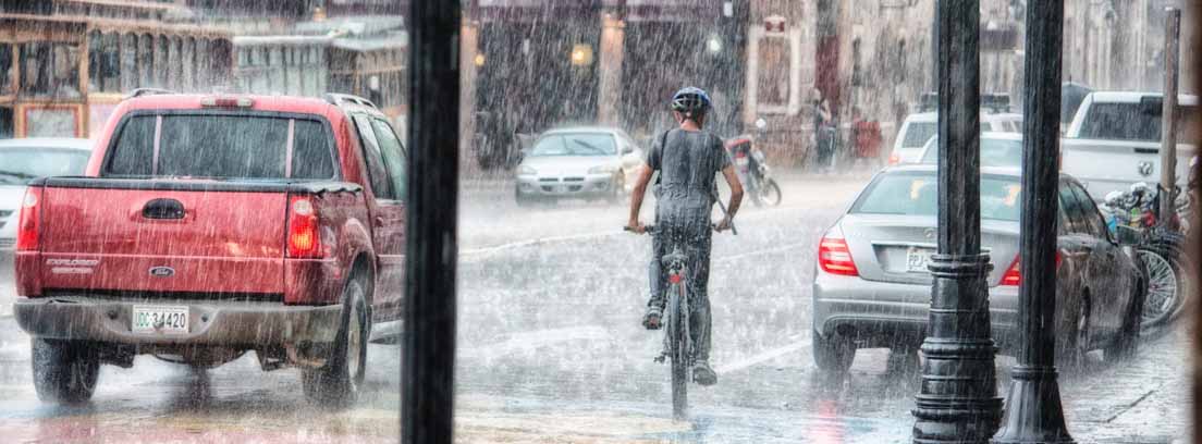 Calle de ciudad con coches y personas bajo una tupida lluvia