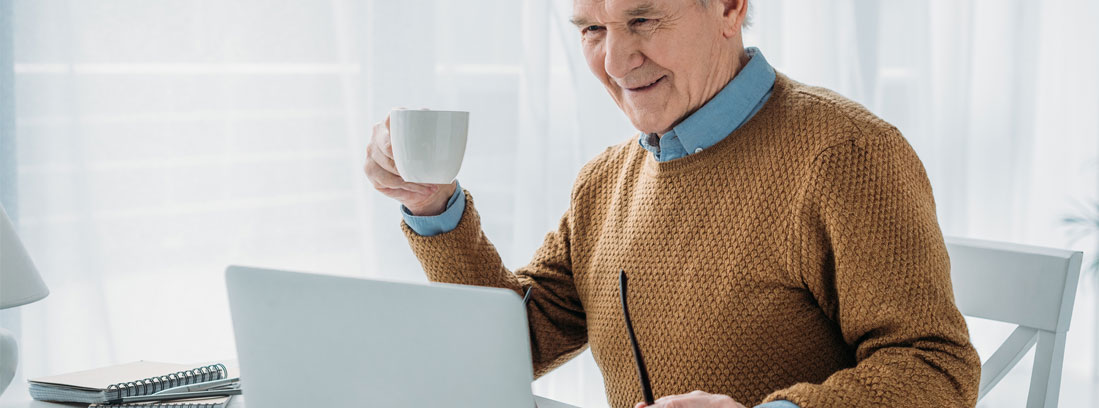 Hombre con pelo blanco delante de ordenador portátil