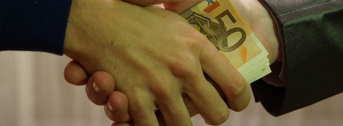 dos manos se pasan un billete de 50 euros