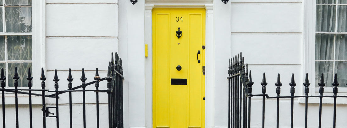 Entrada de una casa con una puerta amarilla y escalones