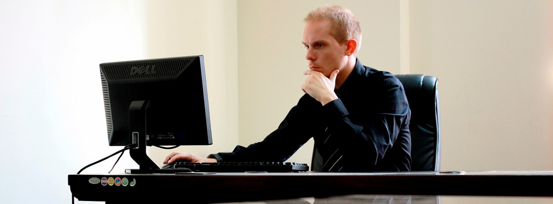 Hombre trajeado sentado frente a un ordenador