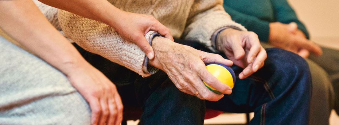 Persona mayor sentada con una pequeña pelota en la mano