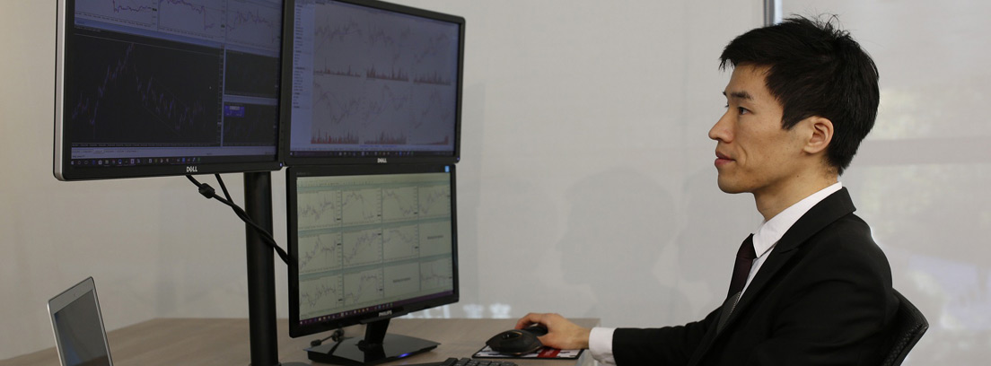 Hombre con chaqueta negra frente a diferentes pantallas de ordenador con gráficos