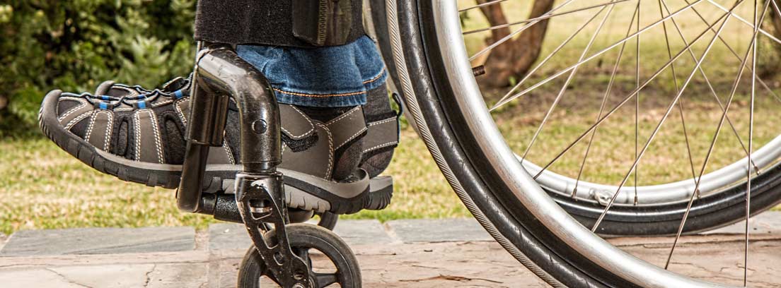 Pies apoyados en el reposapiés de una silla de ruedas