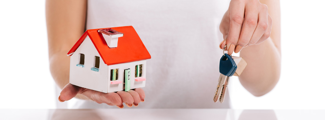 Mujer sosteniendo una maqueta de una casa y unas llaves