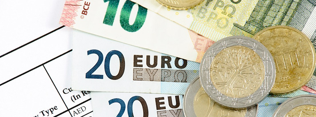Billetes y monedas de euro sobre papel con cotizaciones de monedas extranjeras