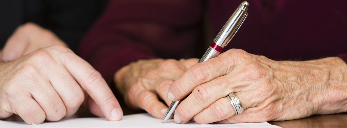 Persona mayor firmando documentos