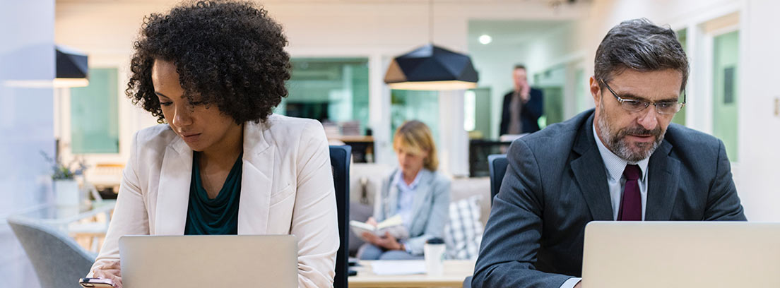 Hombre y mujer sentados en sus puestos de trabajo en una oficina