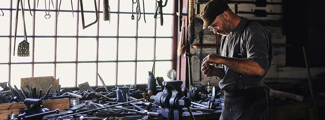 Hombre en taller de soldadura con herramientas y piezas a su alrededor