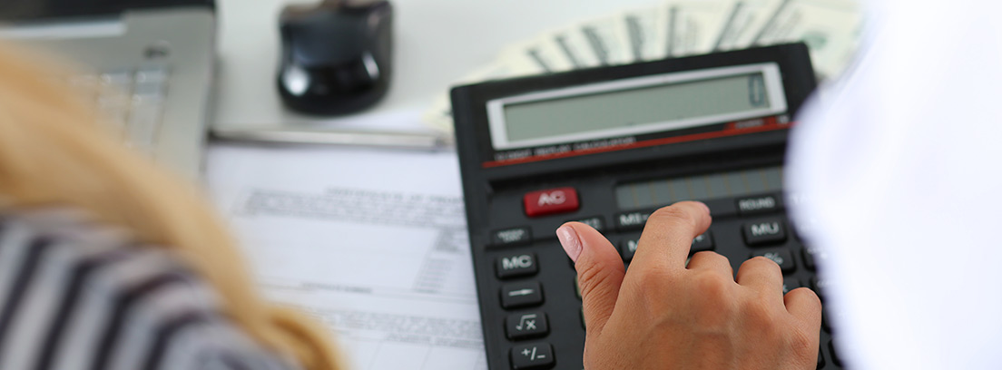 Mujer usando una calculadora para analizar los gastos de la cuesta de septiembre