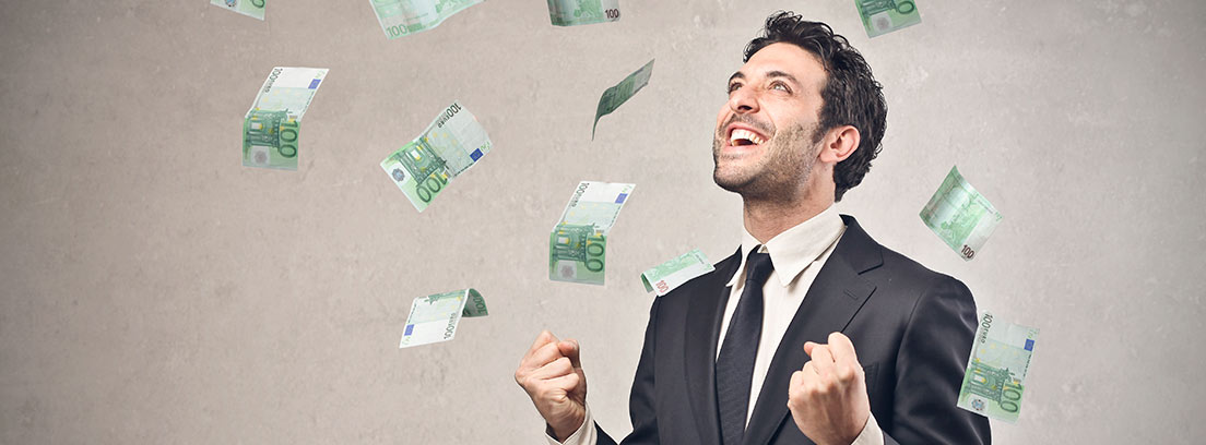 Hombre con traje y gesto sonriente bajo una lluvia de billetes de euro