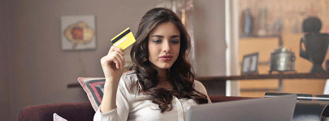 Una mujer sostiene su tarjeta de crédito frente al ordenador