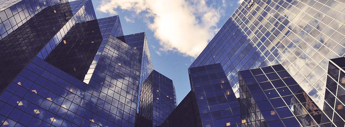 Edificios altos acristalados contra cielo azul con nubes