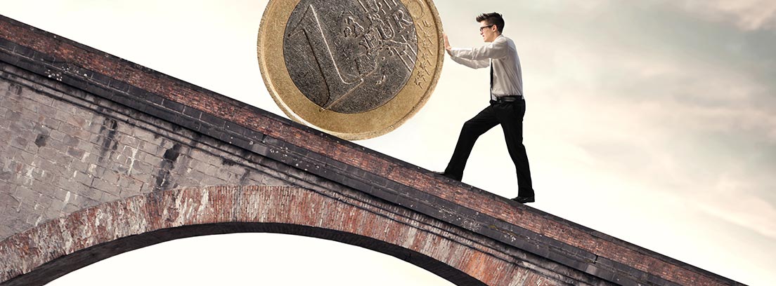 Hombre empujando una moneda de euro por una pendiente