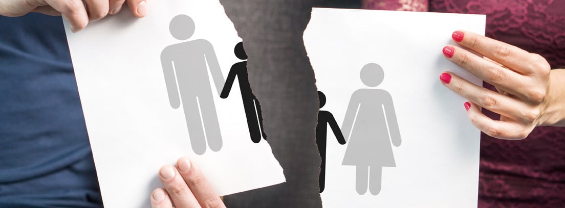 Hombre y mujer sujetando un papel roto con un dibujo de una familia partida por la mitrad