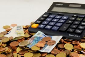 Calculadora rodeado de documentación y cálculos que representan lo que un ahorrador e inversor particular calcula al aportar a su plan de pensiones o a la hora de rescatarlo.