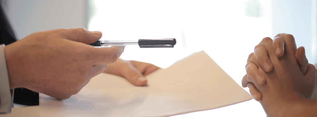 Un profesional ofrece al cliente un bolígrafo para la firma de un documento