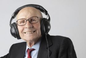 Anciano con traje y corbata escucha música y baila