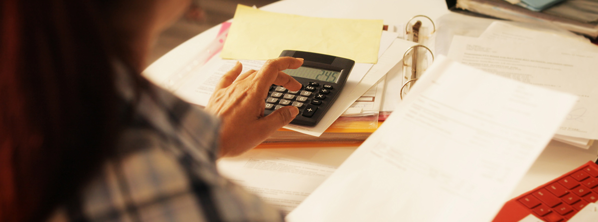 Mujer haciendo cálculos con papeles y una calculadora