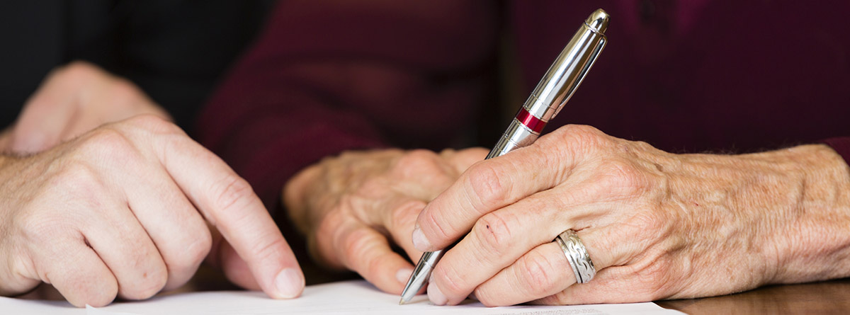 Unas manos sujetando un bolígrafo para firmar un documento