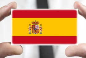 hombre sujetando una tarjeta con la bandera de España