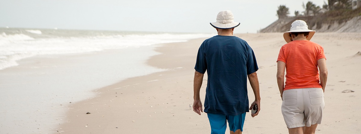 Hombre y mujer de espaldas paseando por la playa