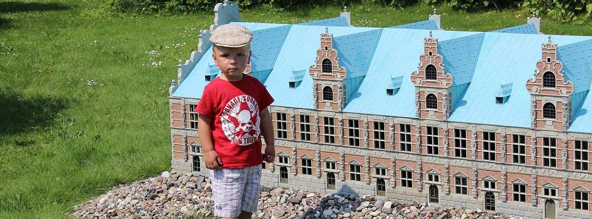 Niño delante de una maqueta de edificio en un terreno