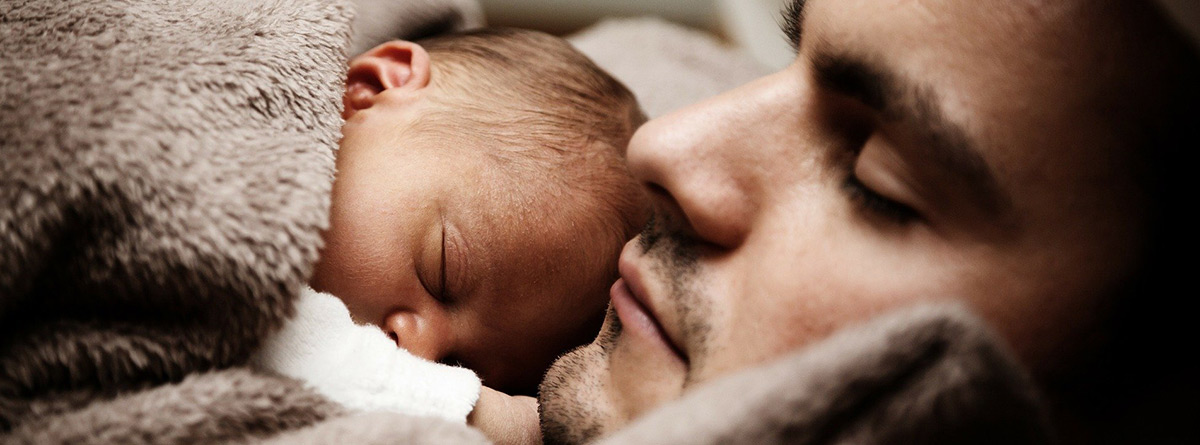 Hombre dormido junto a un bebé