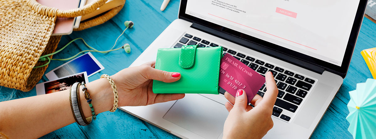 Manos de mujer con tarjeta bancaria frente a un ordenador haciendo un pedido online