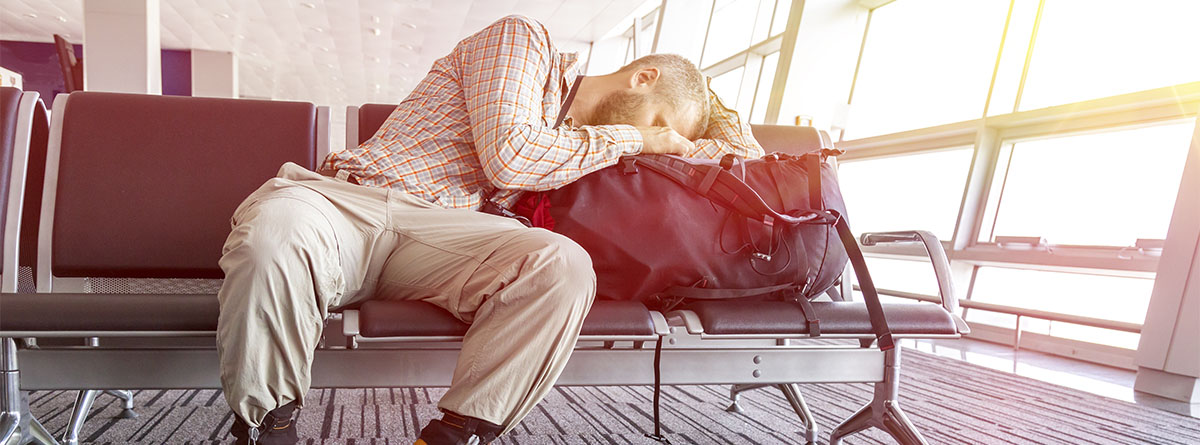 Hombre tumbado sobre su maleta en un aeropuerto