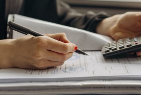 Mujer con documentos y calculadora.