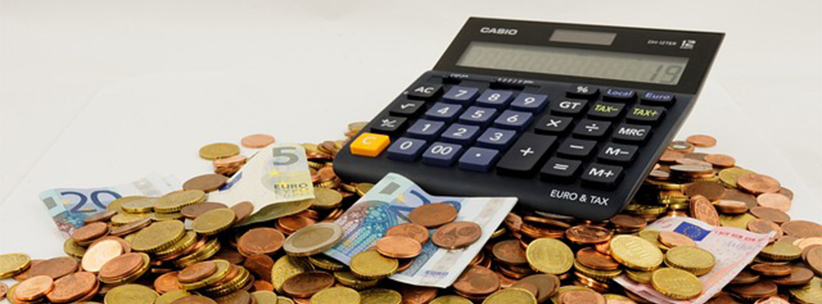 Monedas y billetes de dinero junto con una calculadora como representación del cálculo de la rentabilidad de una inversión.