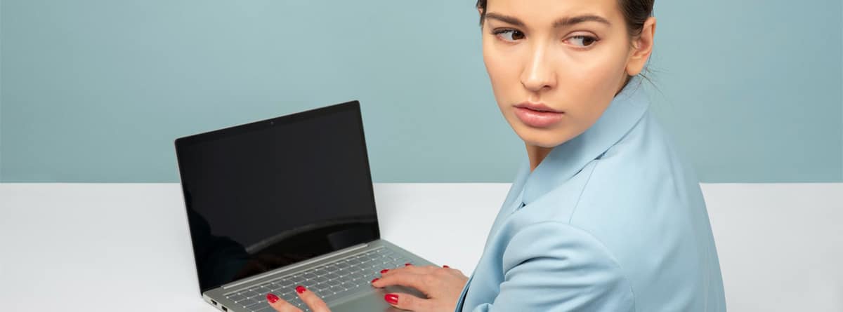 Una mujer sola frente al ordenador gira la cabeza preocupada.