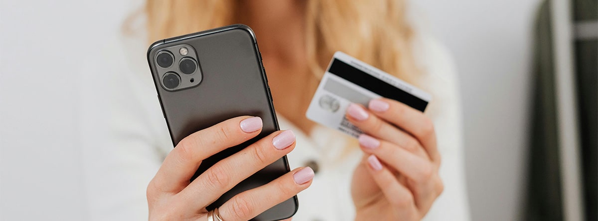 Mujer con un móvil y una tarjeta de crédito