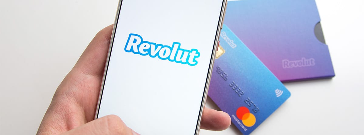 Un móvil con la imagen de “Revolut” y una tarjeta de crédito detrás.