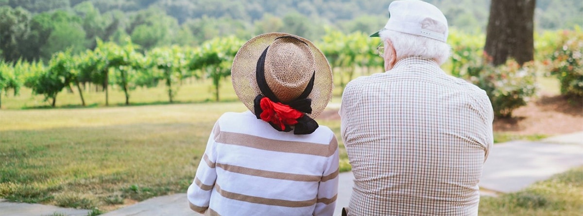 Matrimonio de personas mayores sentados de espaldas en un banco