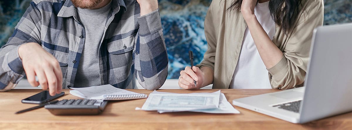 Un hombre y una mujer revisando documentos y utilizando una calculadora